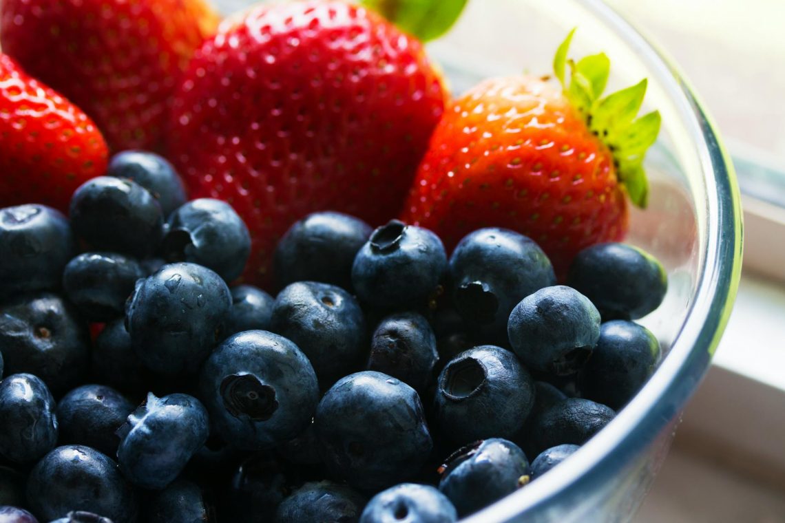 black berries served beside strawberry on clear glass bowl